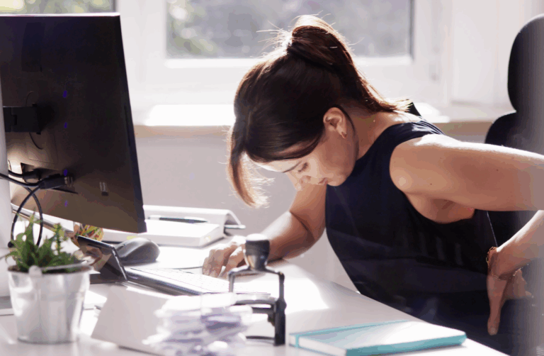 A woman at a desk suffering from a herniated disk | Daniel Stark Law